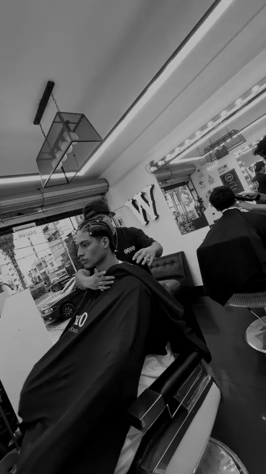 Barbero trabajando en Wencho Barberstudio, con la W en la pared
